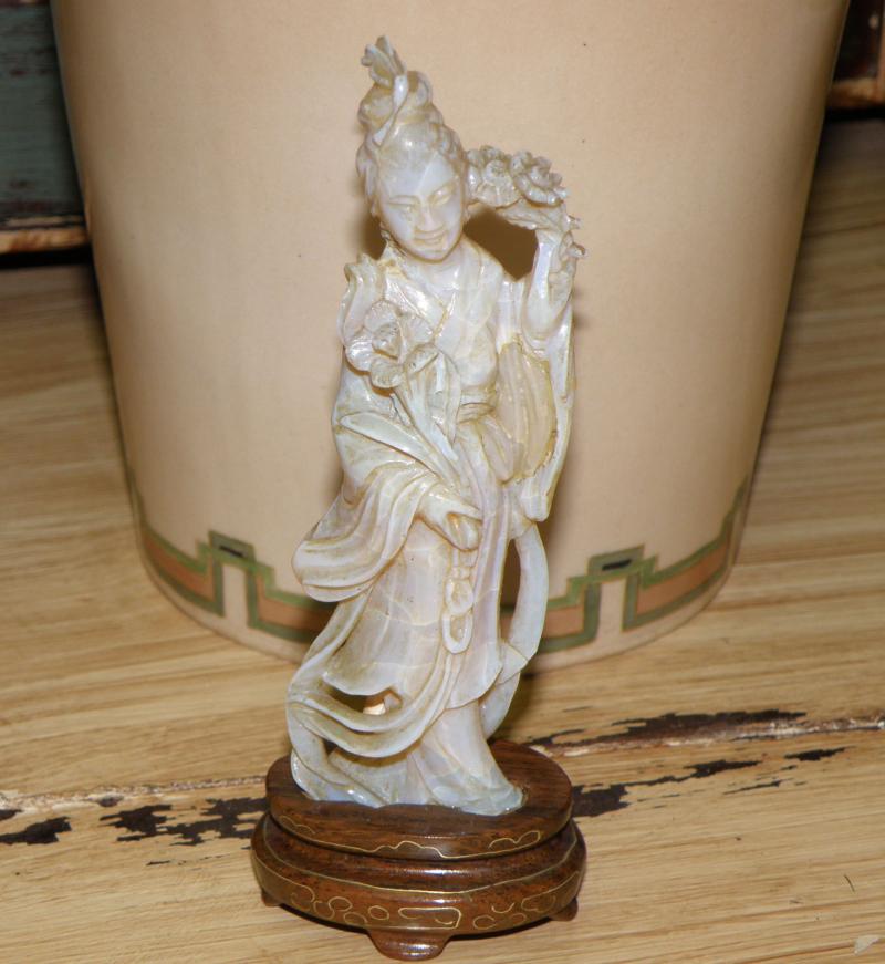 Large Carved Opal Figurine on Stand in front of vase